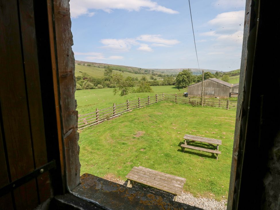 A view of a field with a fence and table from a window at East Barn Bunkhouse