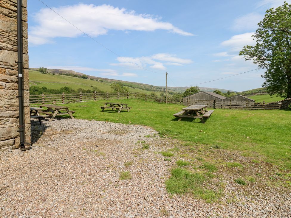 An outdoor area with picnic tables and countryside view at East Barn Bunkhouse