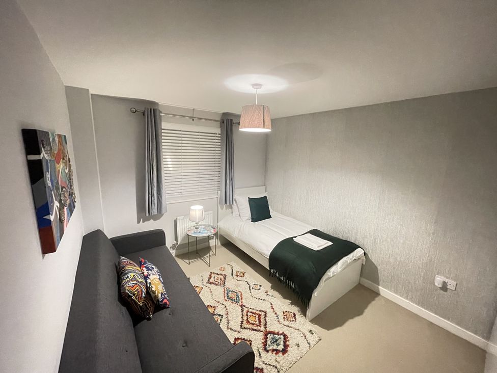 A bedroom with a single bed and a sofa at Derby Den in Breadsall near Derby