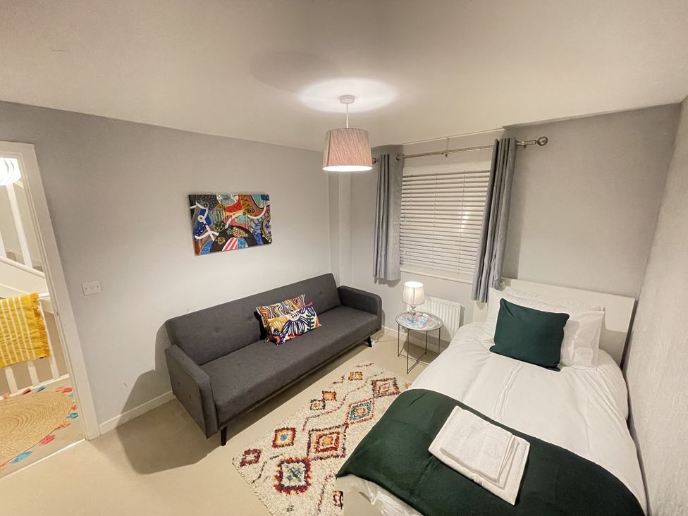 A bedroom with a bed and a sofa at Derby Den in Breadsall near Derby