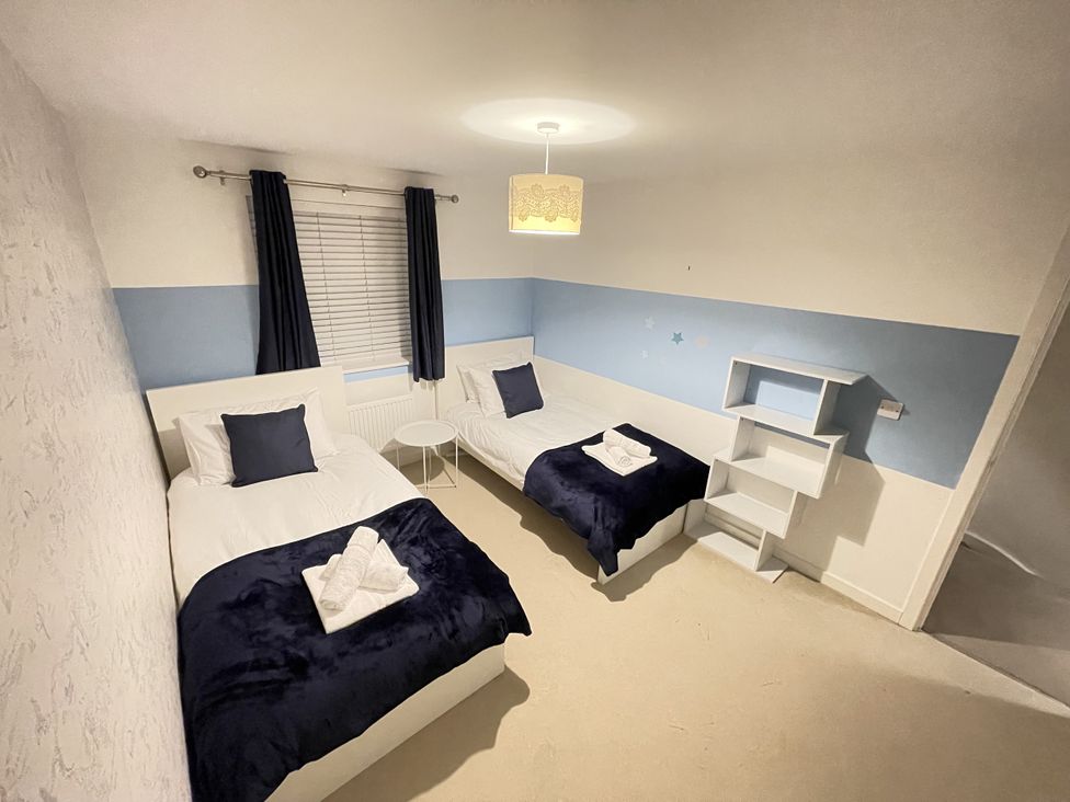 A bedroom with two single beds and a shelf at Derby Den in Breadsall near Derby
