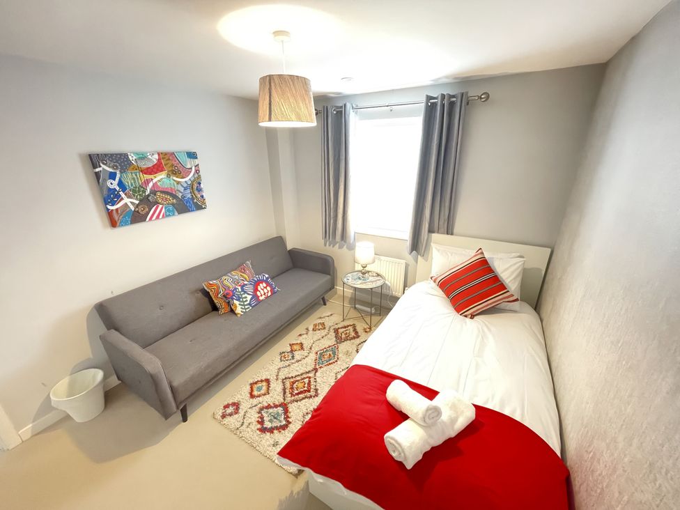 A bedroom with a bed and a sofa at Derby Den in Breadsall near Derby