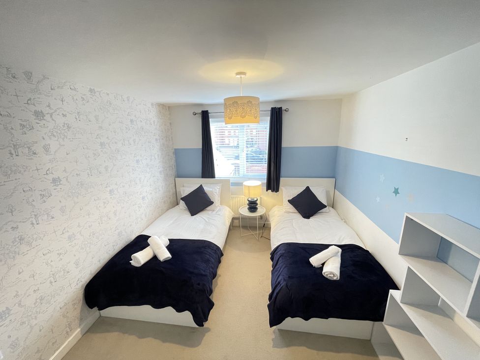 A bedroom with two beds and a bedside table at Derby Den in Breadsall near Derby