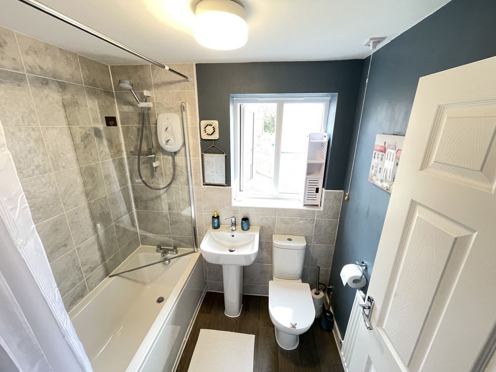 A bathroom with a bathtub, sink, and toilet at Derby Den in Breadsall near Derby