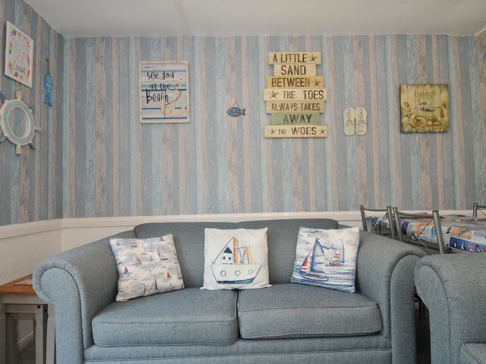 A living room with a blue sofa and decorative pillows at 13 Hillside in Bude