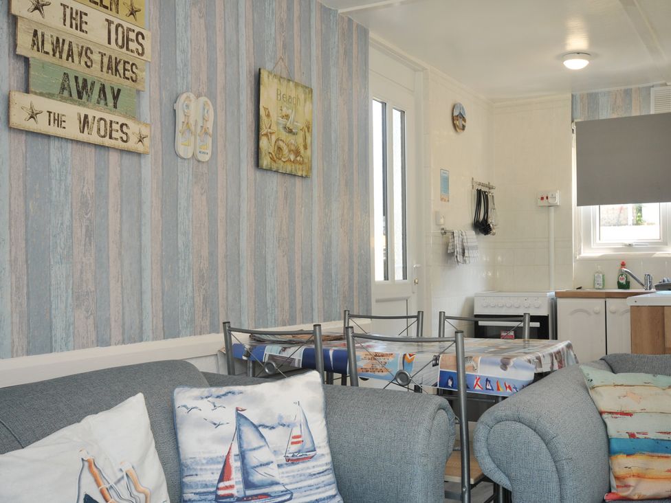 A living room with a sofa, table and chairs at 13 Hillside in Bude