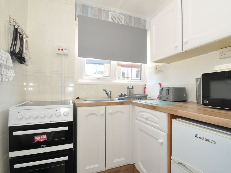 A kitchen with an oven, sink, and appliances at 13 Hillside in Bude