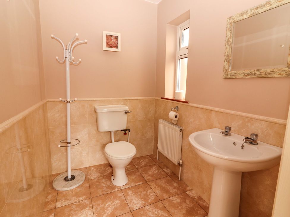 A bathroom with a toilet, sink, and coat rack at 51 Woodview Park in Tralee, County Kerry