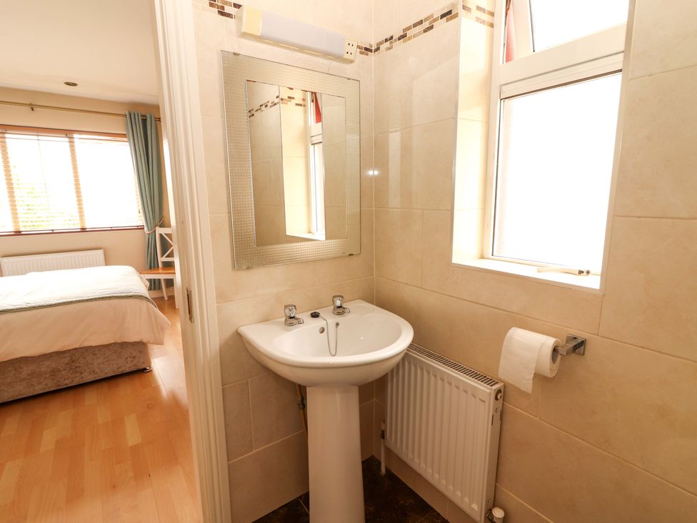 A bathroom with a pedestal sink and window at 51 Woodview Park in Tralee, County Kerry