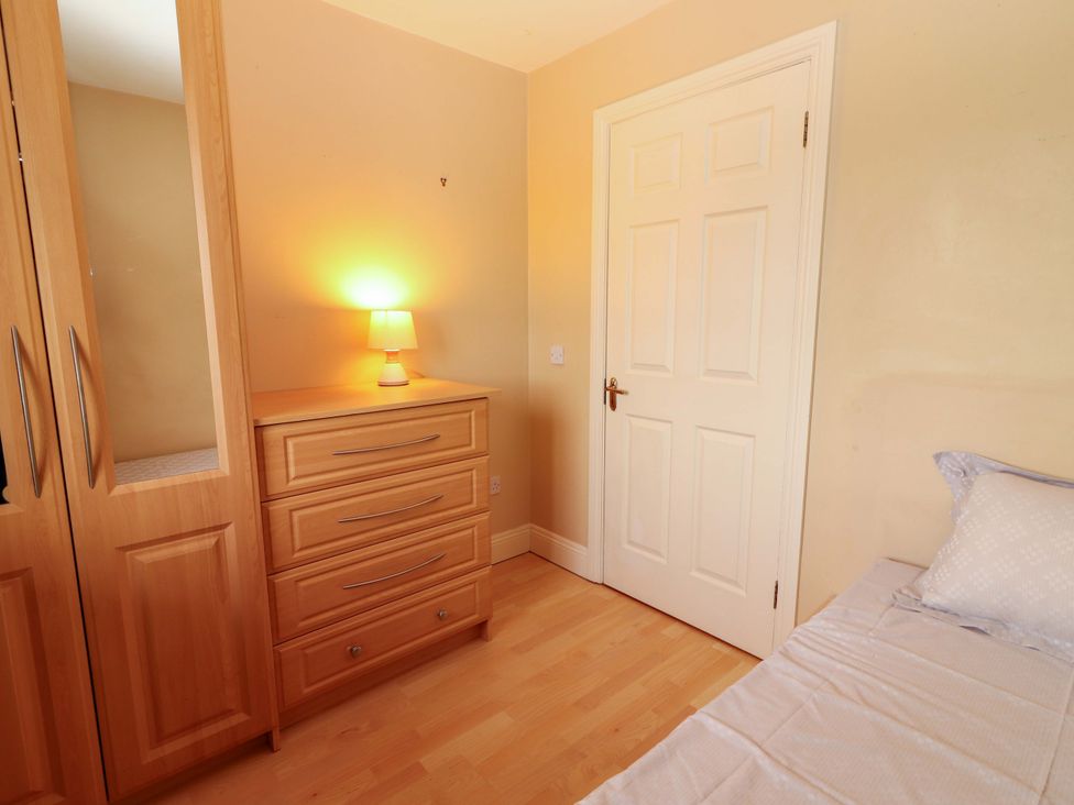 A bedroom with a wardrobe, chest of drawers, lamp and bed at 51 Woodview Park, Tralee, County Kerry