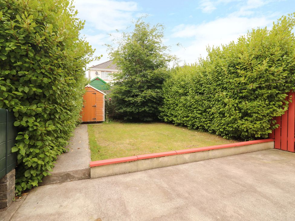 A garden with hedges, grass, and a garden shed at 51 Woodview Park, Tralee, County Kerry