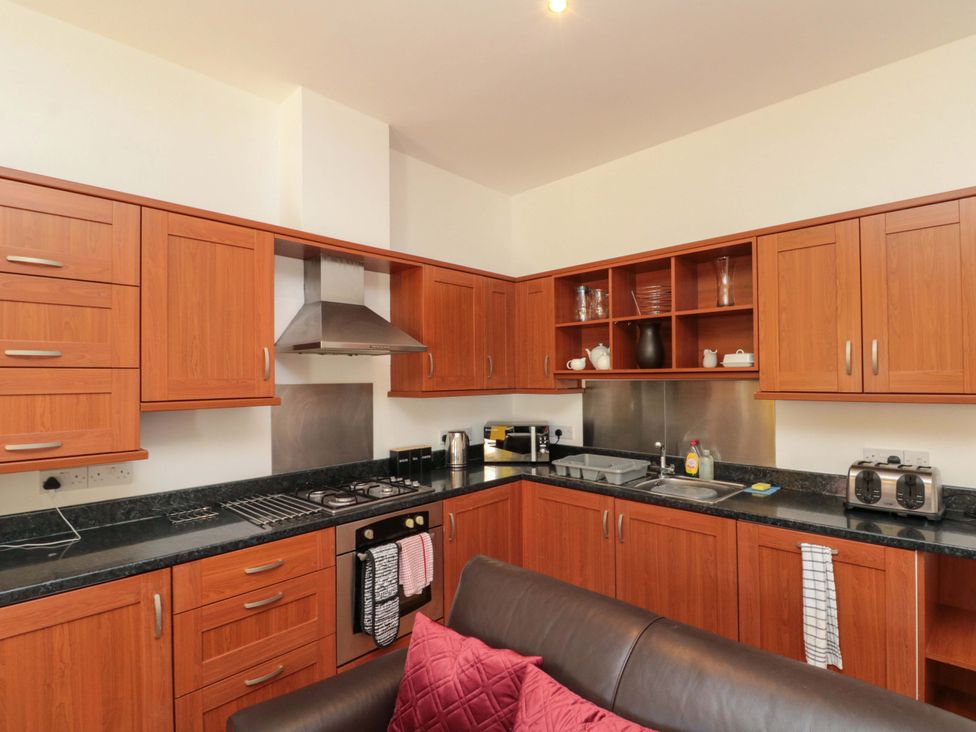 A kitchen with wooden cabinets and appliances at Farriers Cottage in Bridlington