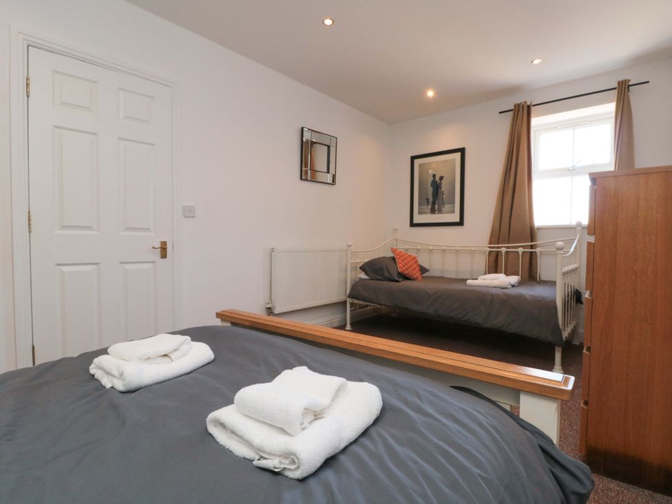 A bedroom with two beds and towels arranged at Farriers Cottage in Bridlington
