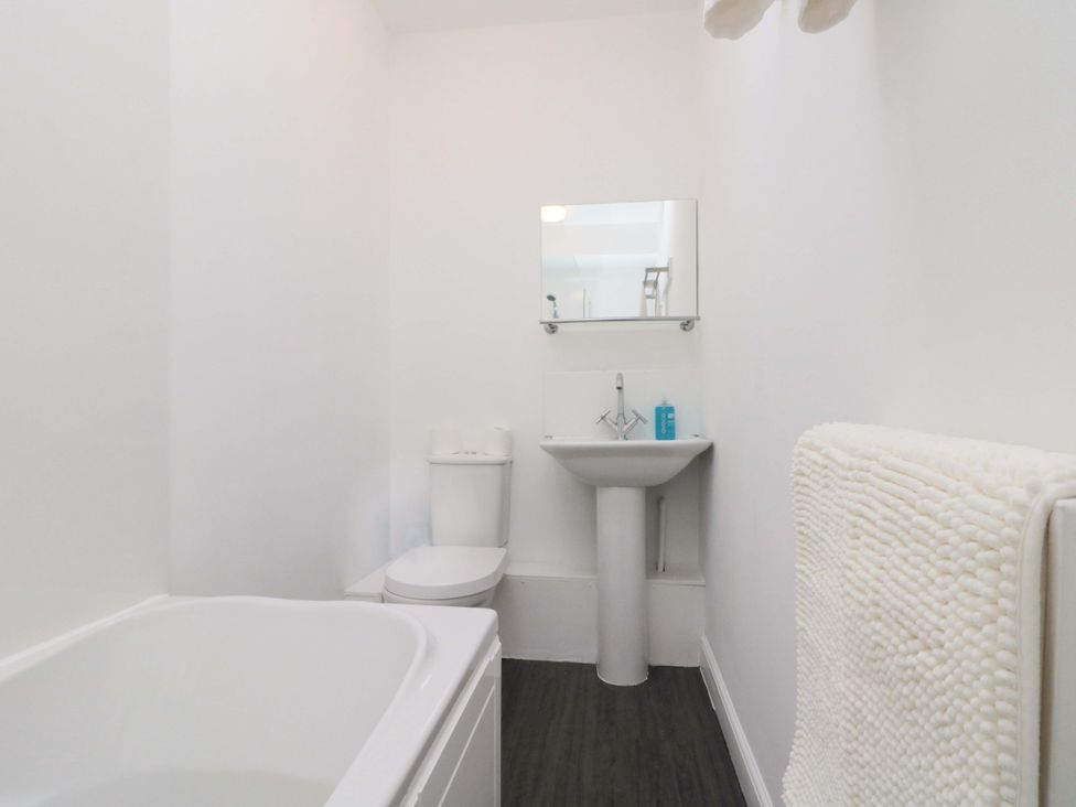 A bathroom with a bathtub, toilet, and sink at Farriers Cottage in Bridlington