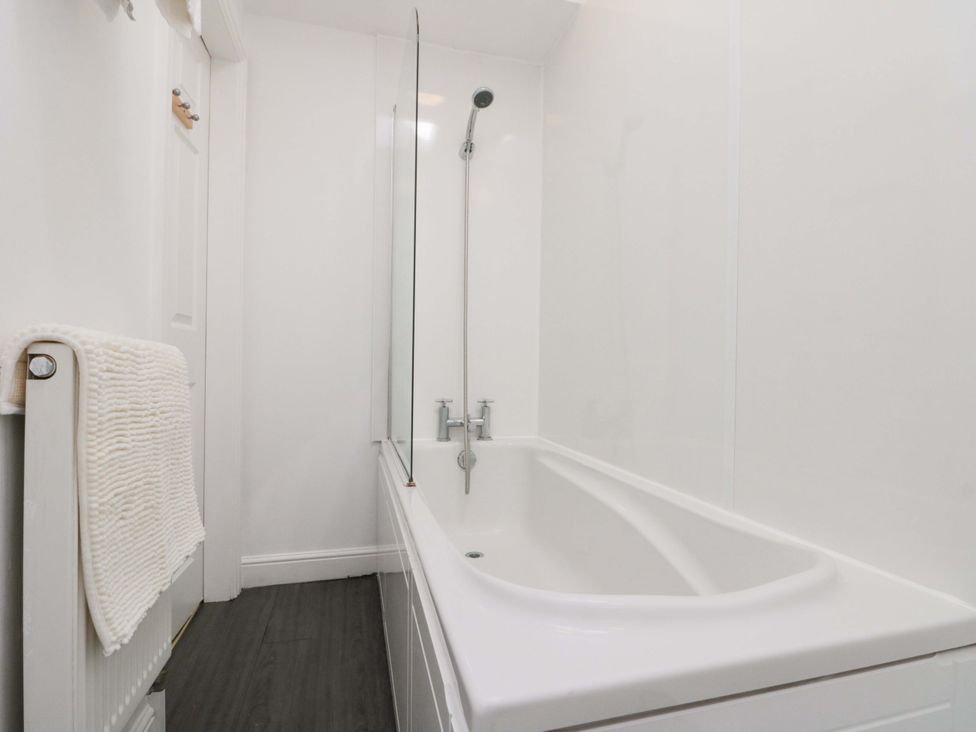 A bathroom with a bathtub and a showerhead at Farriers Cottage in Bridlington