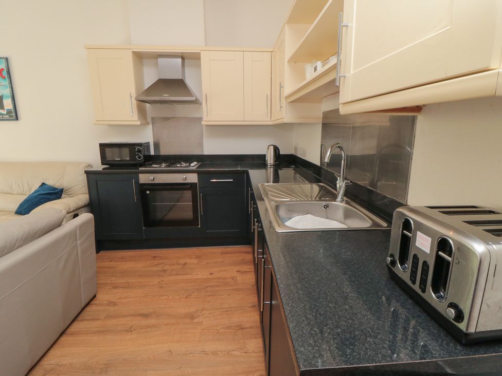 A kitchen with microwave, oven, stove, sink, and toaster at 2 Londesborough Mews in Bridlington