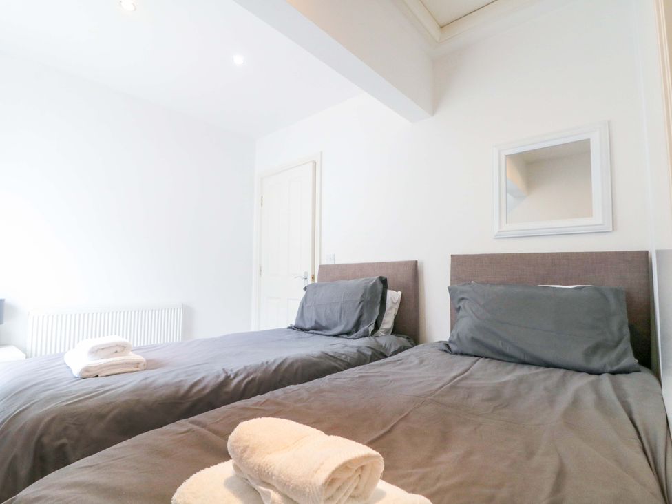 A bedroom with two beds and towels on the beds at Chestnut Cottage in Bridlington