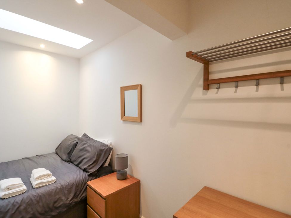 A bedroom with a bed, table, lamp, and shelf at Chestnut Cottage in Bridlington
