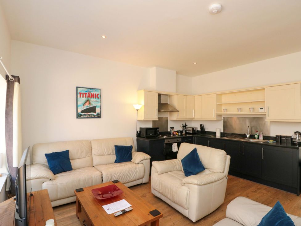A living room with a sofa and kitchen area at Chestnut Cottage in Bridlington