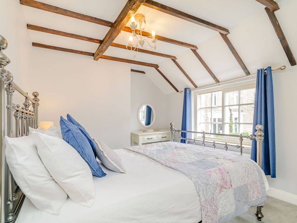 A bedroom with a bed and mirror at Chimes Cottage in Guisborough