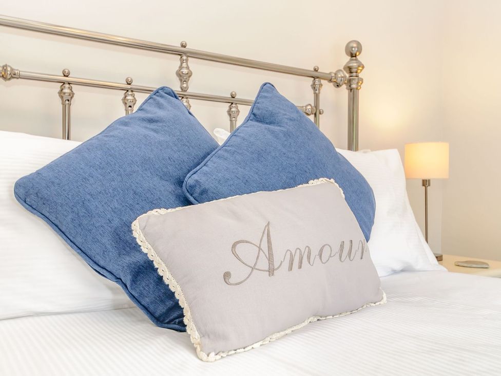 A bed with blue pillows and a lamp at Chimes Cottage in Guisborough