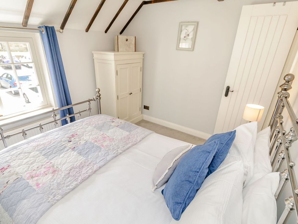 A bedroom with a bed and wardrobe at Chimes Cottage in Guisborough