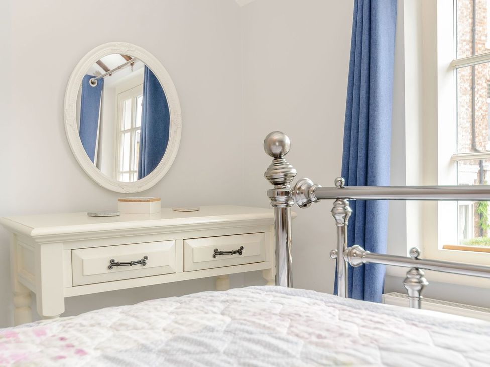 A bedroom with a dresser and mirror at Chimes Cottage in Guisborough