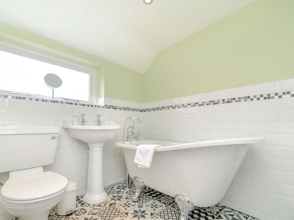 A bathroom with a bathtub, toilet, and sink at Chimes Cottage in Guisborough