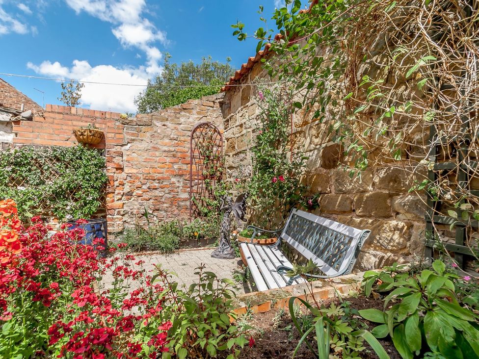 A garden with flowers and a bench at Chimes Cottage in Guisborough