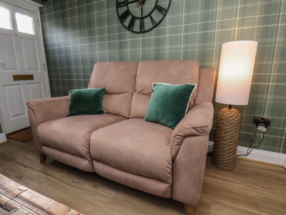 A living room with a sofa and lamp at Chimes Cottage in Guisborough