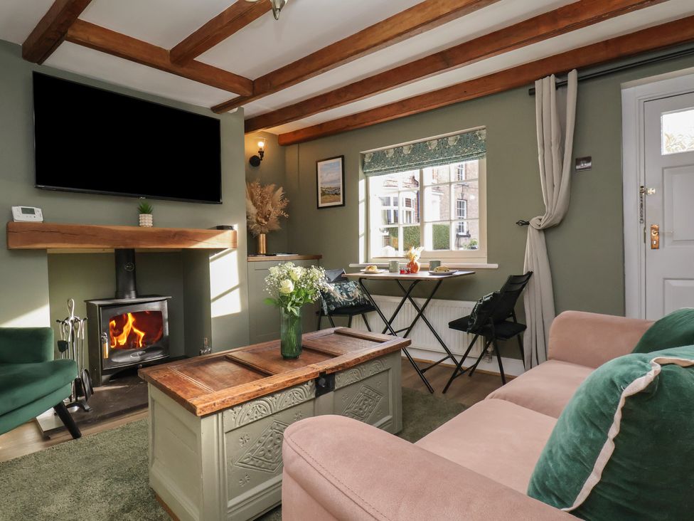 A living room with a fireplace and table at Chimes Cottage in Guisborough