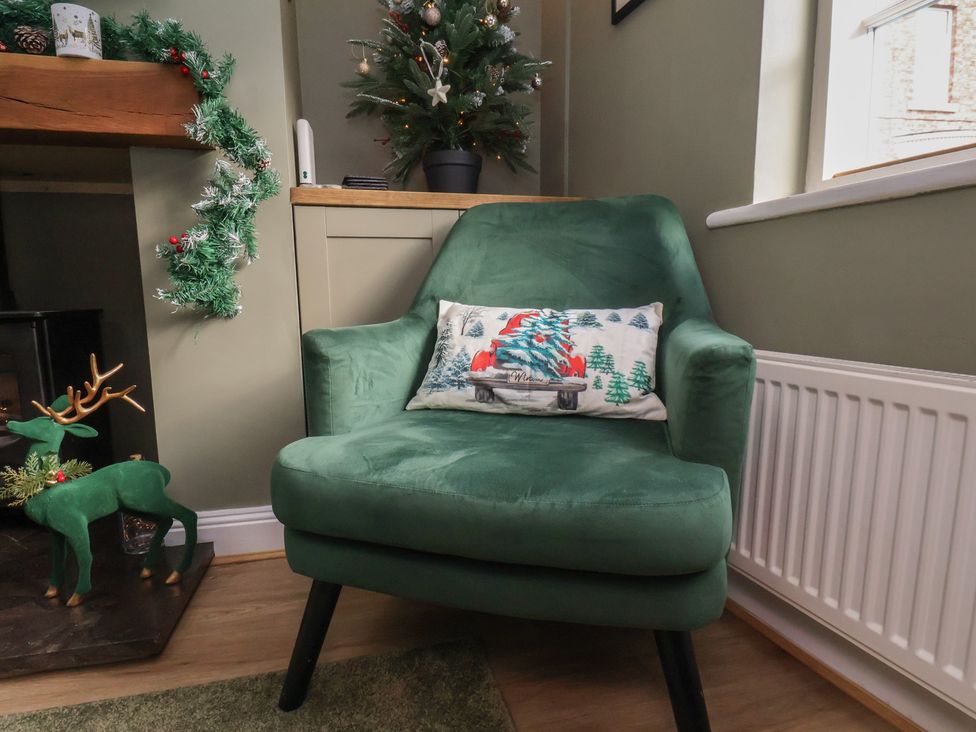 A living room with a green chair and decorative items at Chimes Cottage in Guisborough