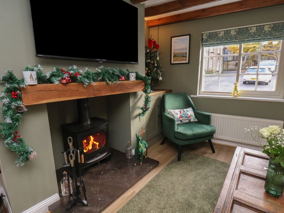 A living room with a fireplace and a chair at Chimes Cottage in Guisborough