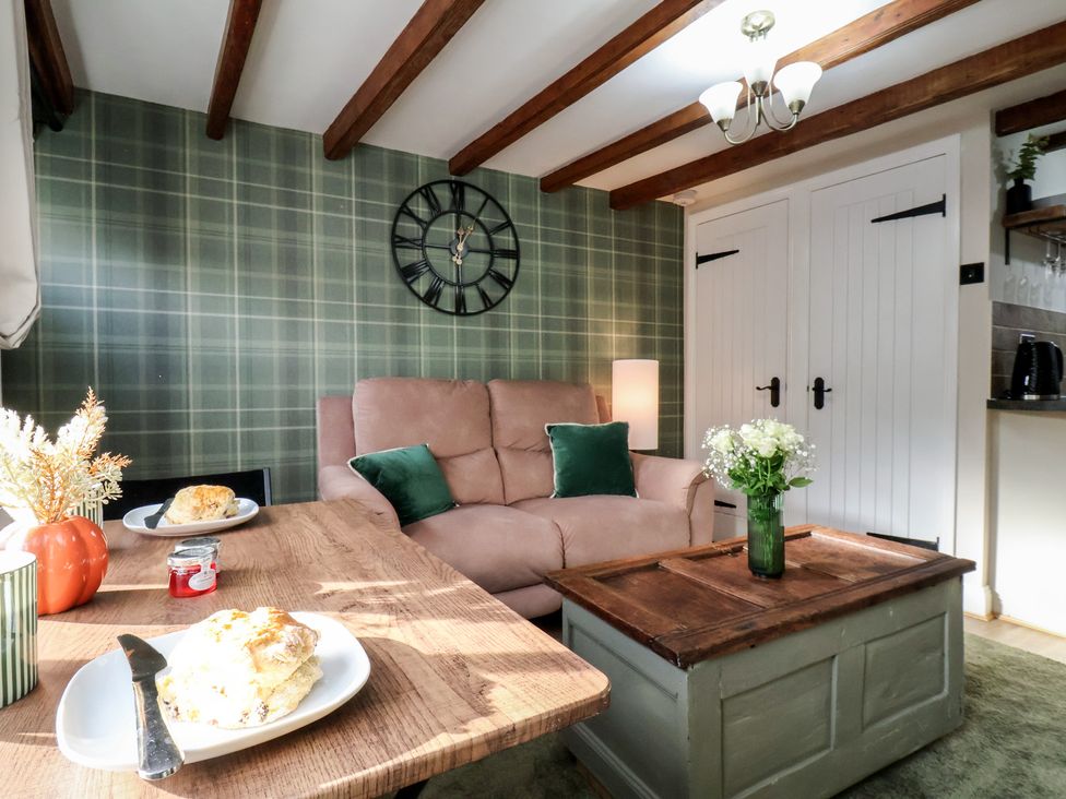 A living room with a couch, table and clock at Chimes Cottage in Guisborough