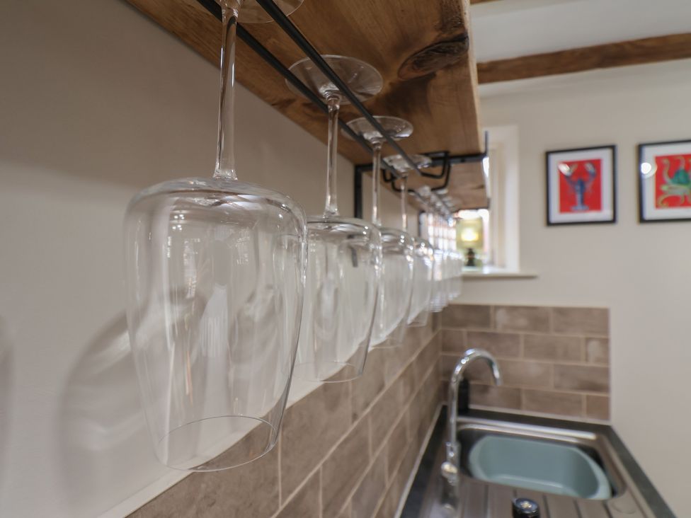 A kitchen with hanging glasses and a sink at Chimes Cottage in Guisborough