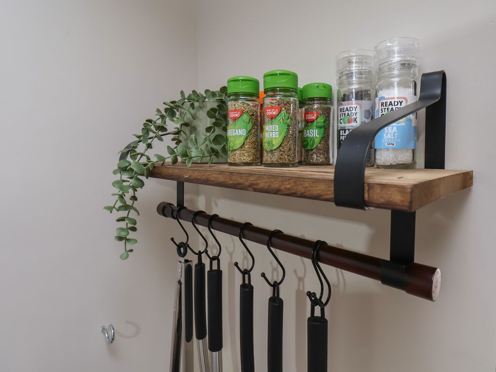 A shelf with spices and a plant in a kitchen at Chimes Cottage in Guisborough