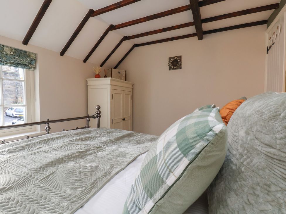 A bedroom with a metal bed and wardrobe at Chimes Cottage in Guisborough