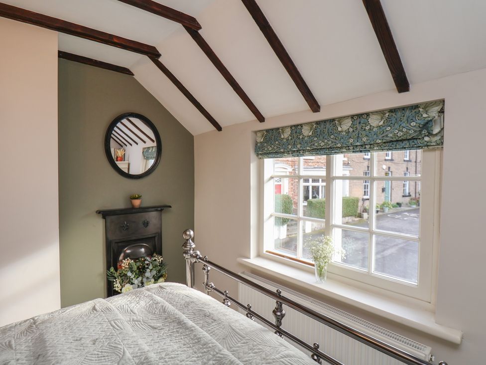 A bedroom with a window and flowers on the sill at Chimes Cottage in Guisborough
