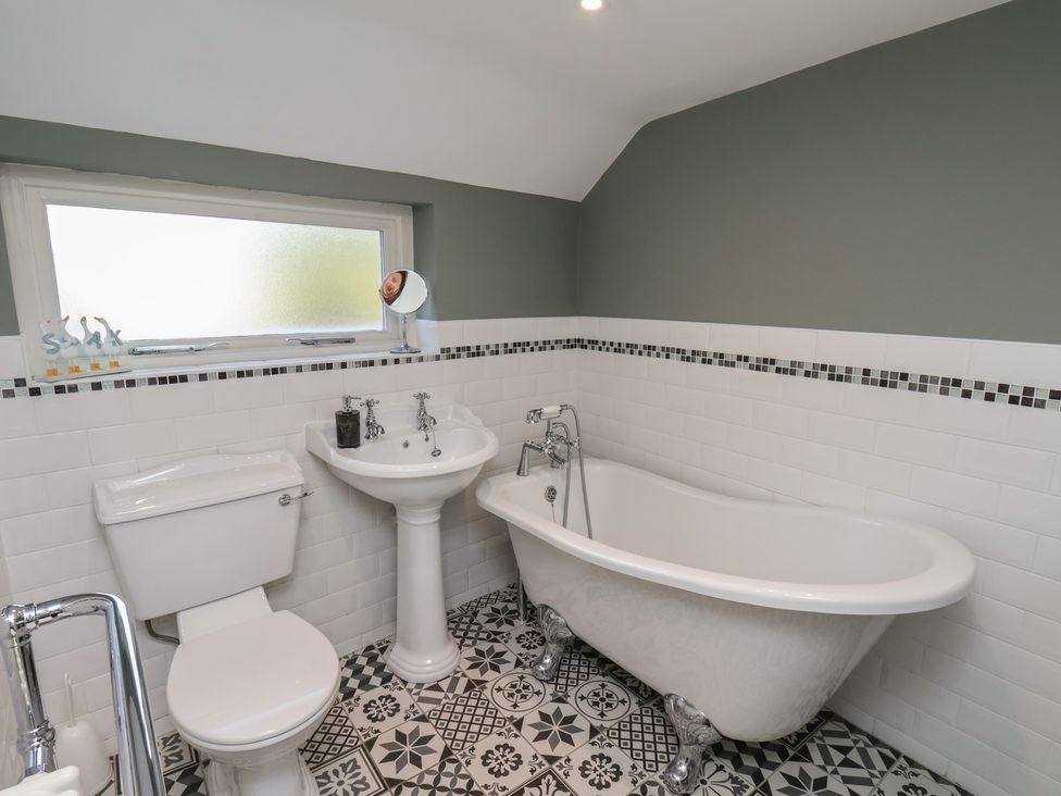 A bathroom with a bath tub and wash basin at Chimes Cottage in Guisborough