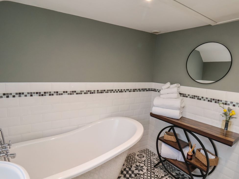 A bathroom with a bathtub and towels at Chimes Cottage in Guisborough