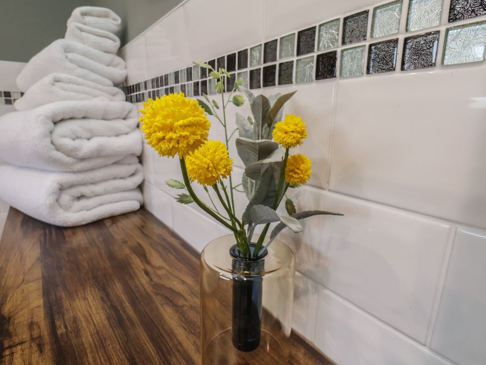 A bathroom with towels and a flower vase at Chimes Cottage in Guisborough