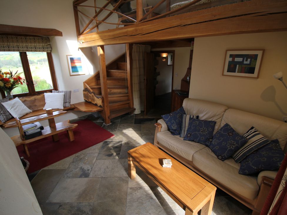 A living room with a sofa and stairs at The Dovecote in Fishguard