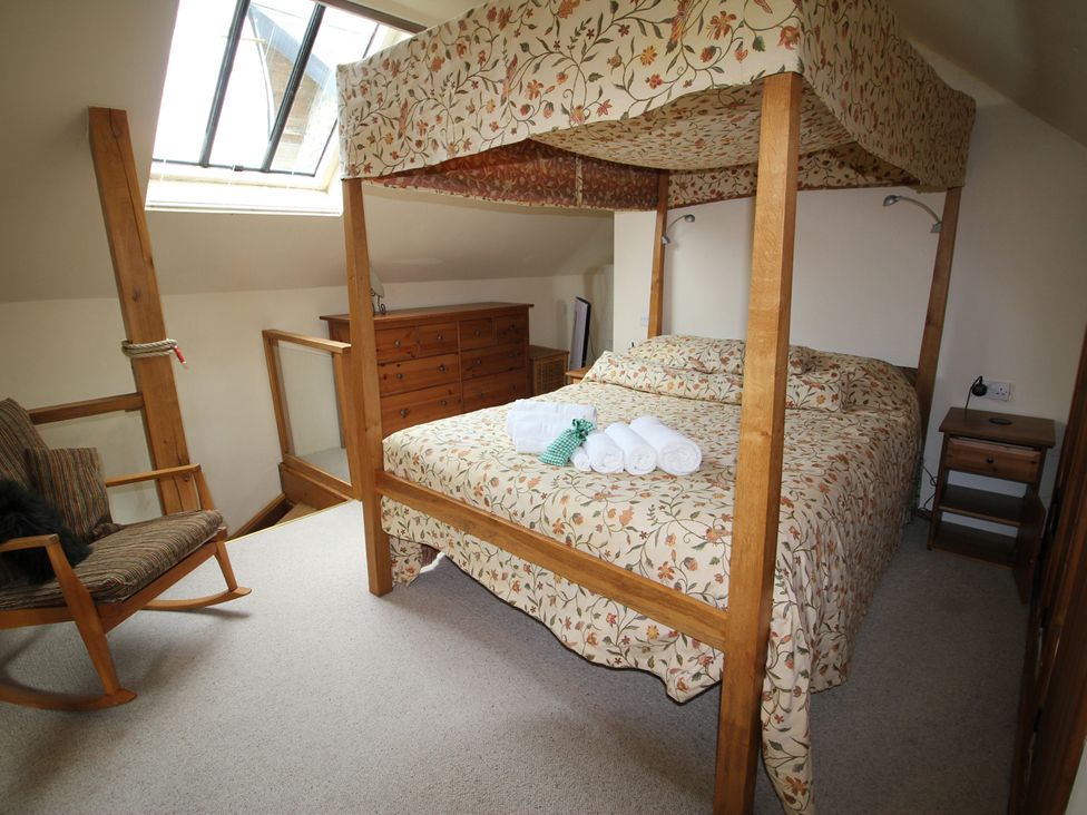 A bedroom with a four-poster bed and wooden furniture at The Dovecote in Fishguard