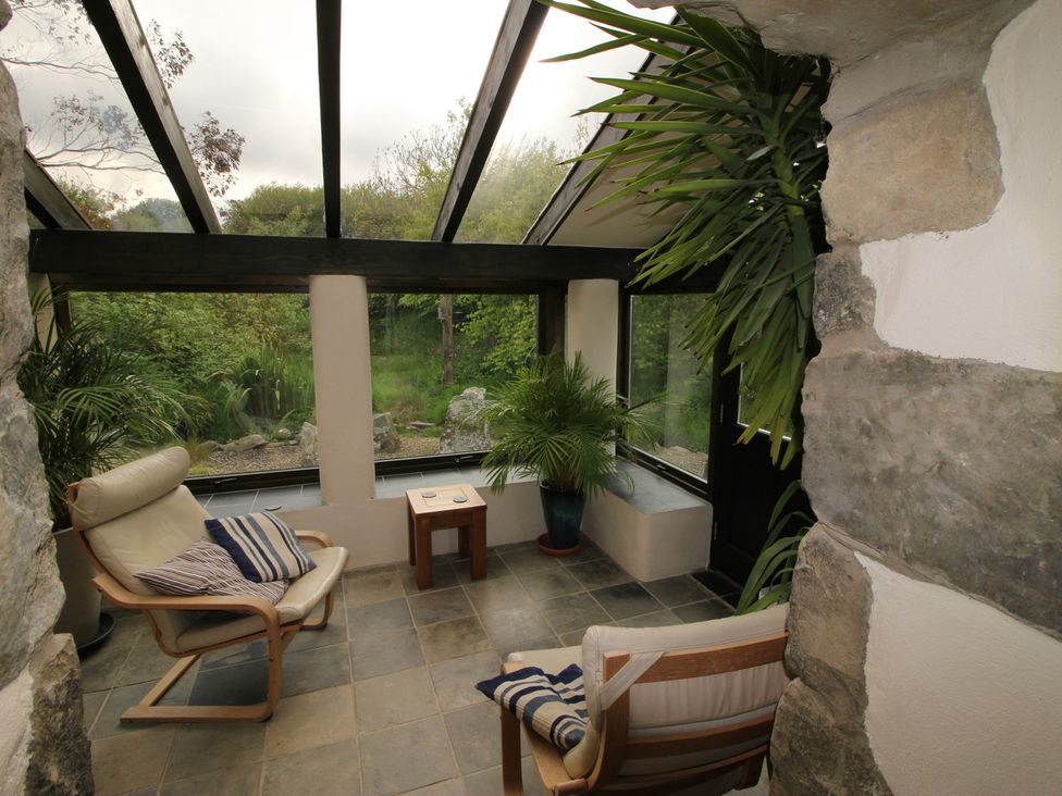 A conservatory with furniture and plants at The Dovecote in Fishguard
