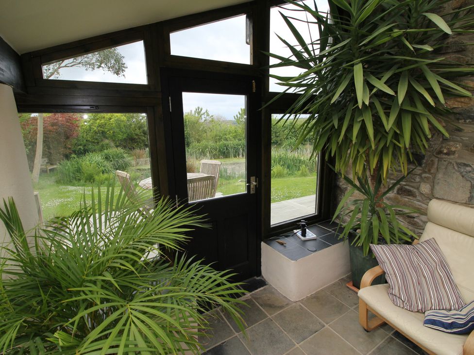 A conservatory with a door and large windows at The Dovecote in Fishguard