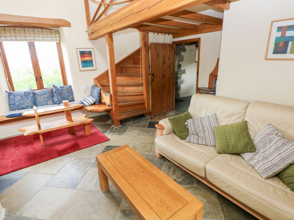 A living room with a sofa, coffee table, and staircase at The Dovecote in Llanychaer near Fishguard