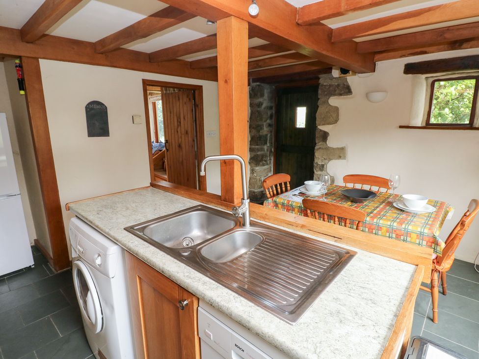A kitchen with a sink and dining area at The Dovecote in Llanychaer near Fishguard
