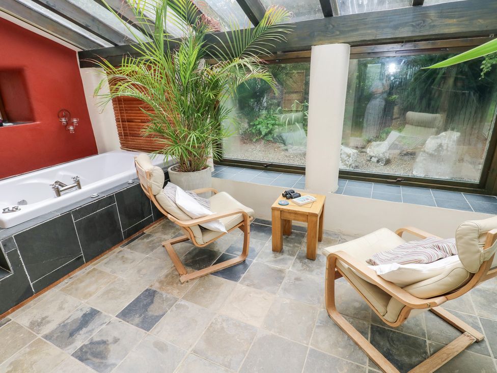 A conservatory with a bathtub and seating area at The Dovecote Llanychaer near Fishguard