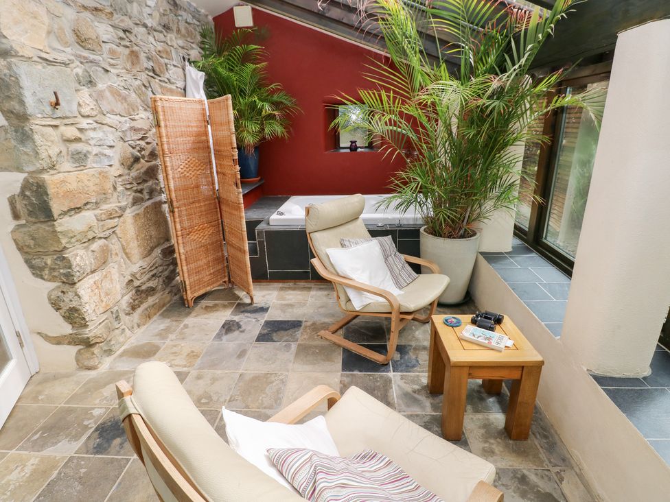 A sunroom with a chair and a table in The Dovecote Llanychaer near Fishguard