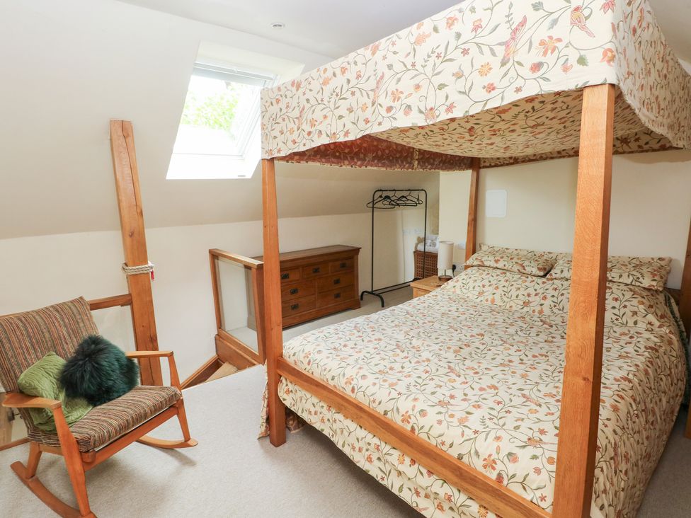 A bedroom with a canopy bed and rocking chair at The Dovecote in Llanychaer near Fishguard